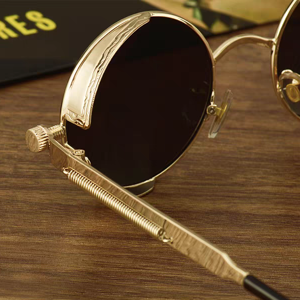 Gold-framed sunglasses with black lenses on a wooden surface