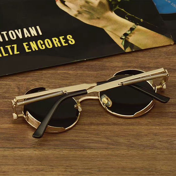 Gold-framed sunglasses on a wooden surface with a vinyl record in the background