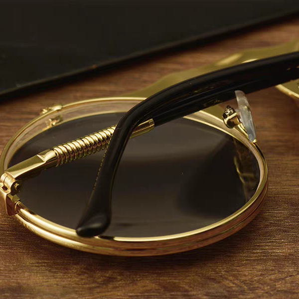 Gold-framed sunglasses with black lenses on a wooden surface