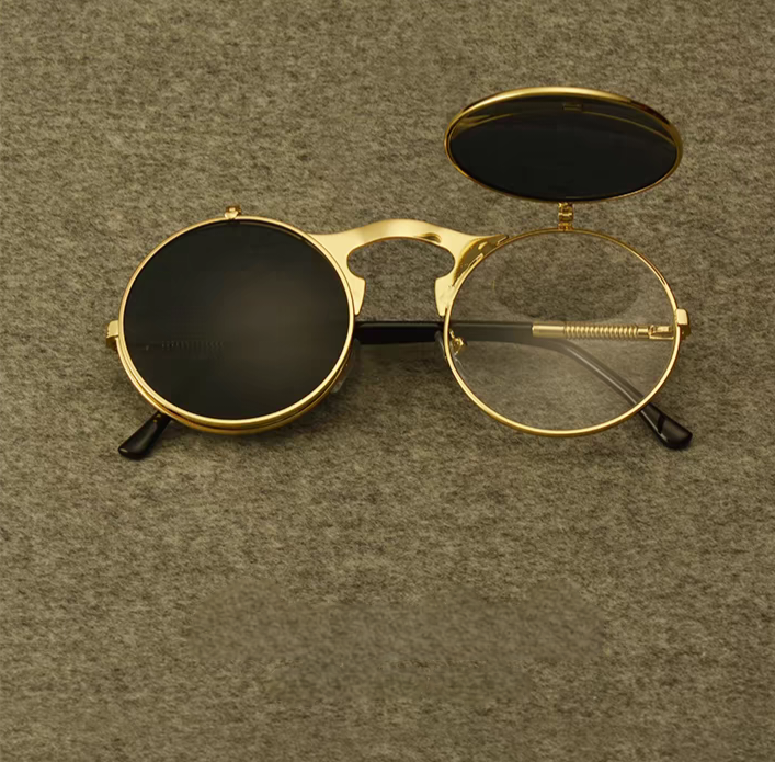 Gold-framed sunglasses with black lenses on a textured brown background