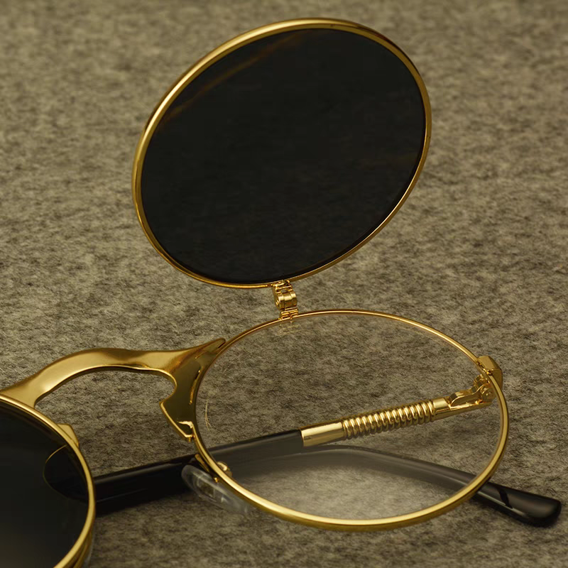 Gold-rimmed sunglasses with a magnifying glass on a textured brown background