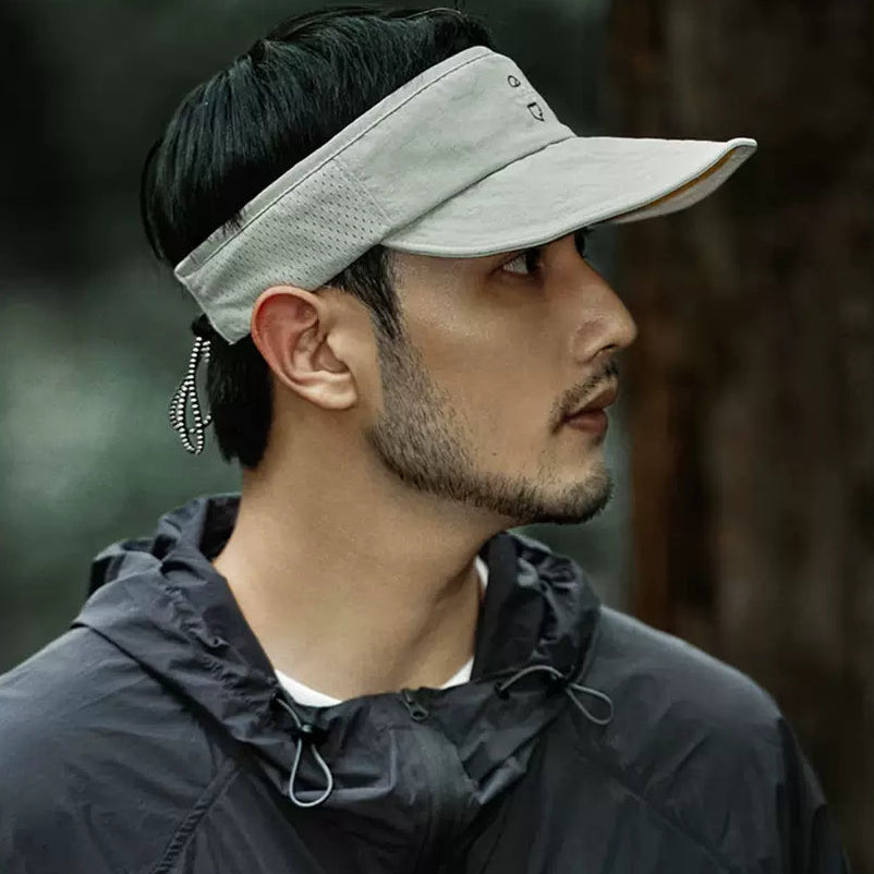 Man wearing a light gray visor outdoors with a blurred natural background