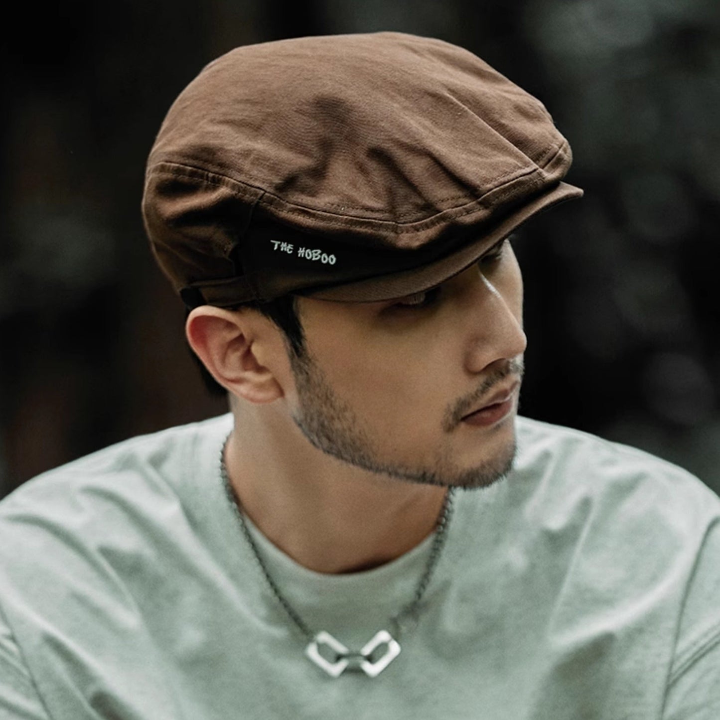 Man wearing a brown cap and light green shirt with a blurred background
