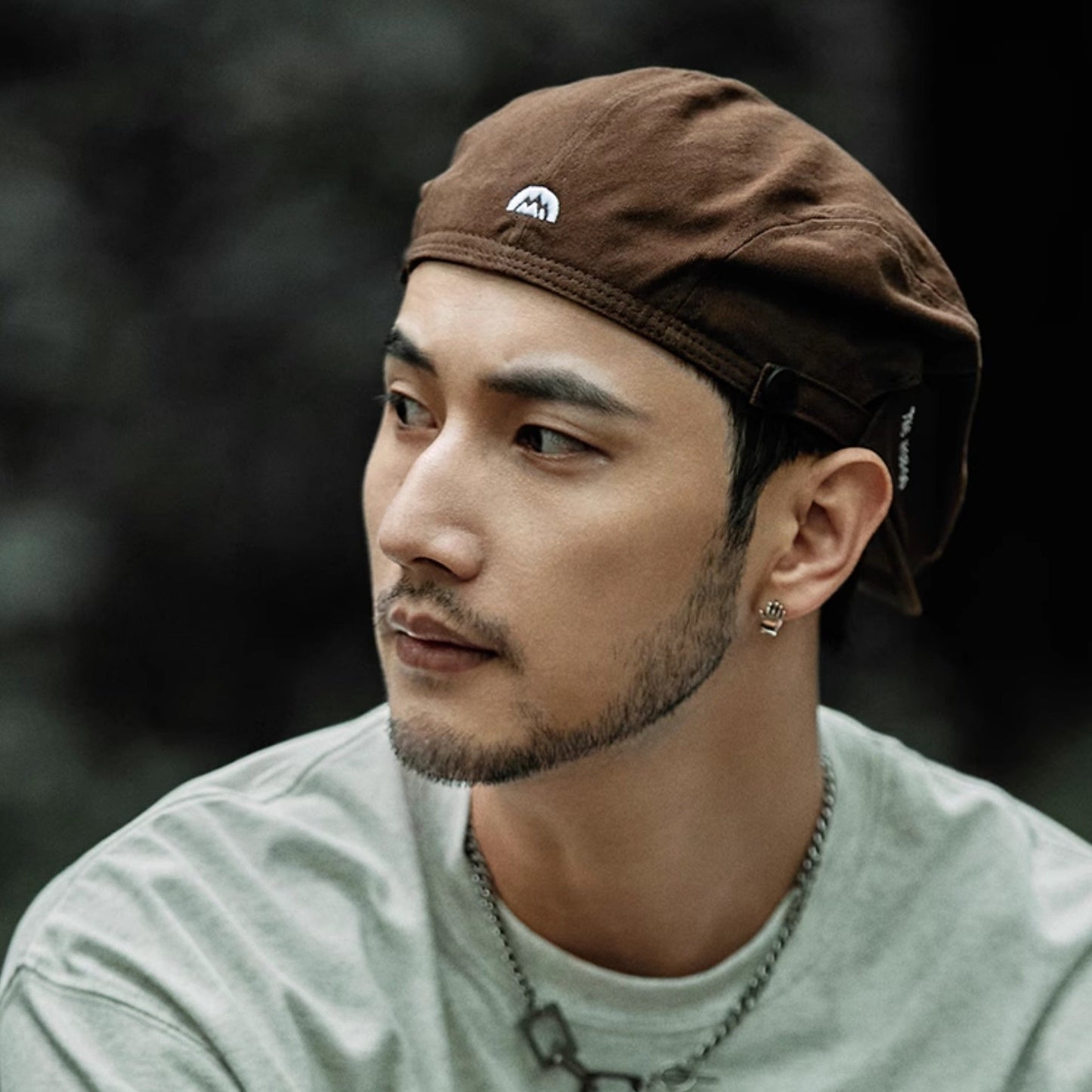 Man wearing a brown cap and light green shirt with a blurred background