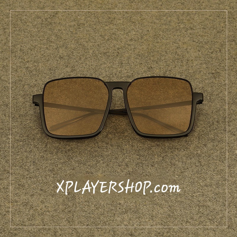 Sunglasses with brown lenses and black frames on a textured brown background with 'XPLAYERSHOP.com' text.