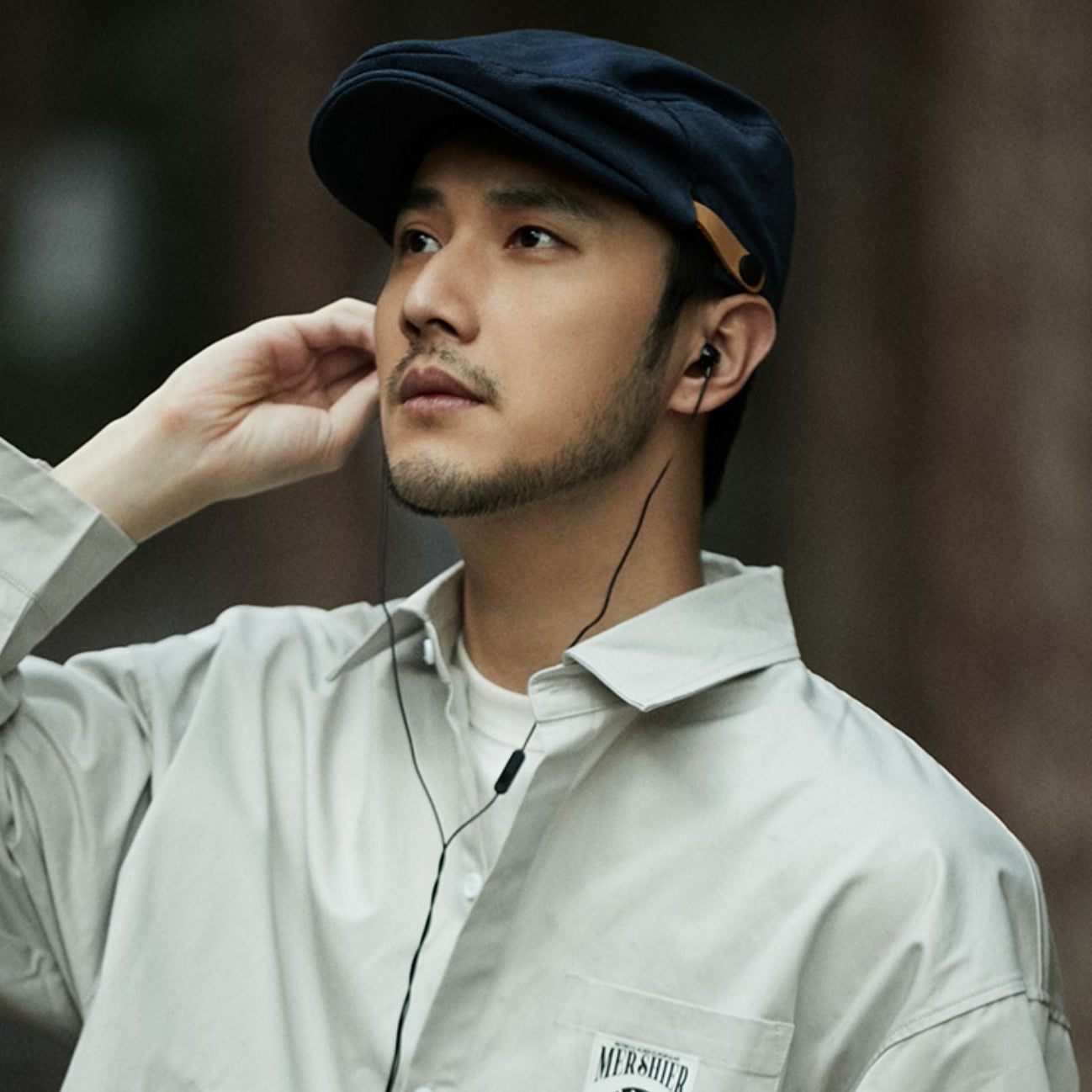 Man wearing a cap and light-colored shirt with a blurred background