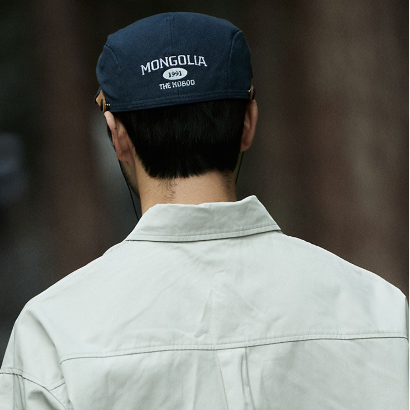 Person wearing a blue cap with 'Mongolia' text, facing away from the camera.
