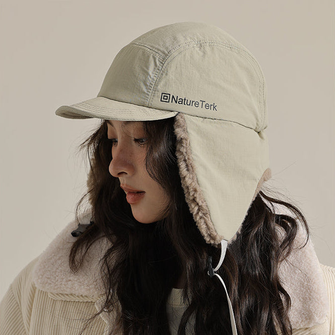 Person wearing a beige cap with a hood and Nature Tek logo, standing against a neutral background.