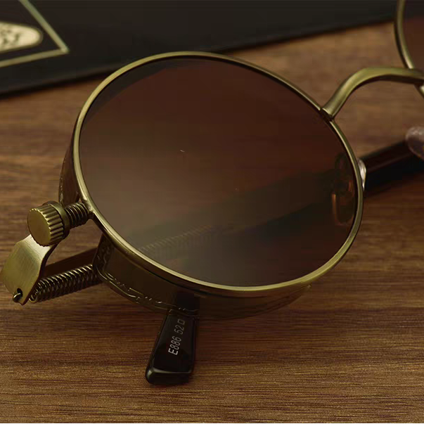 Vintage-style sunglasses with brown lenses and gold frames on a wooden surface.