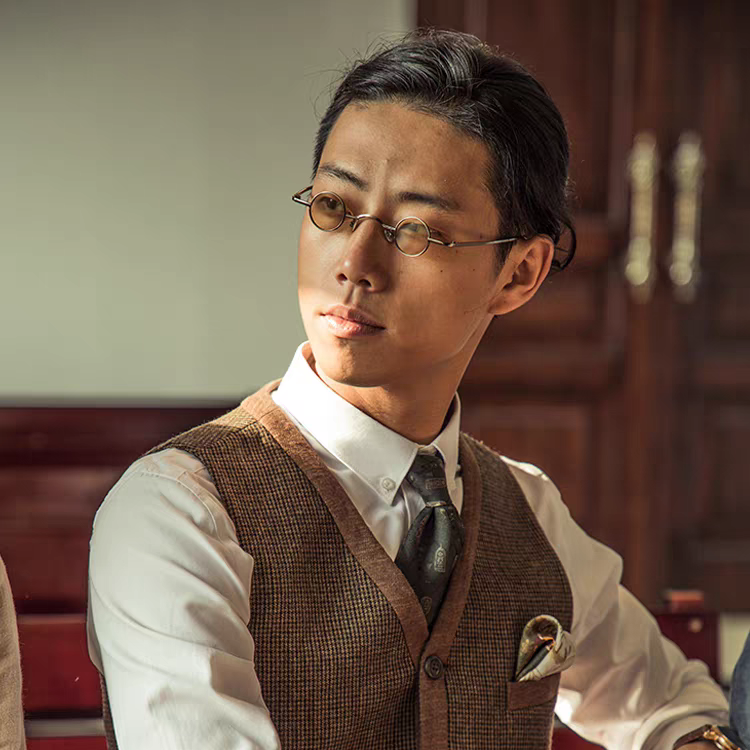 Man wearing glasses and a brown vest in an indoor setting