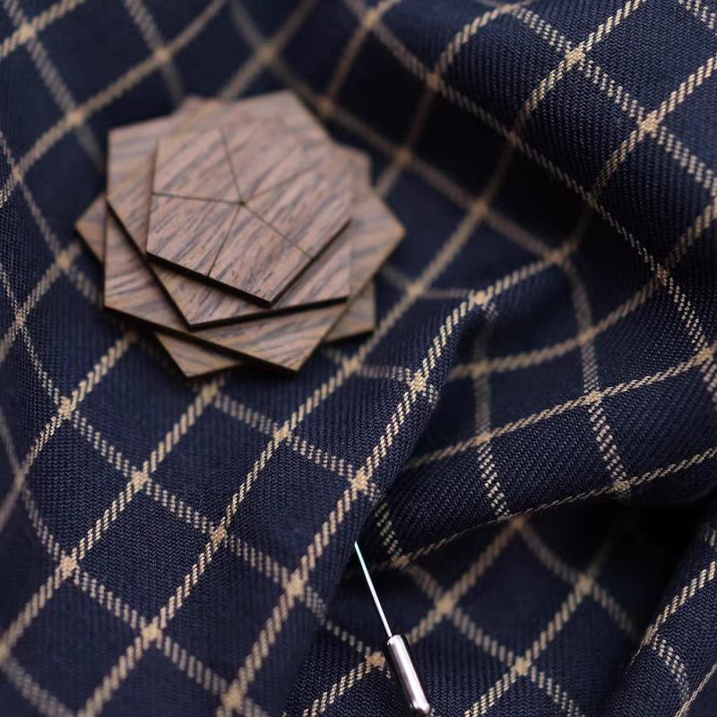 Wooden geometric pin on a navy blue fabric with white check pattern