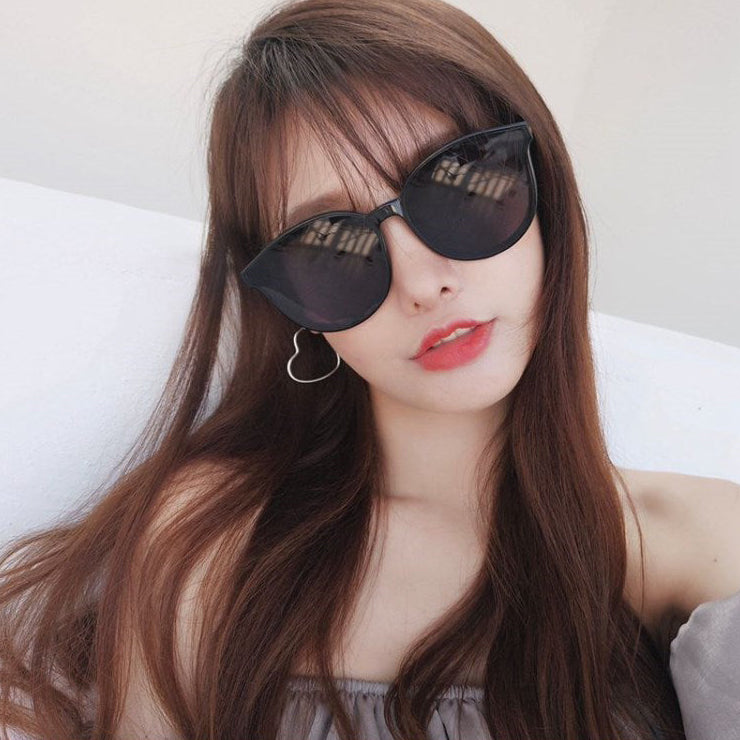 Woman wearing black sunglasses with a neutral background