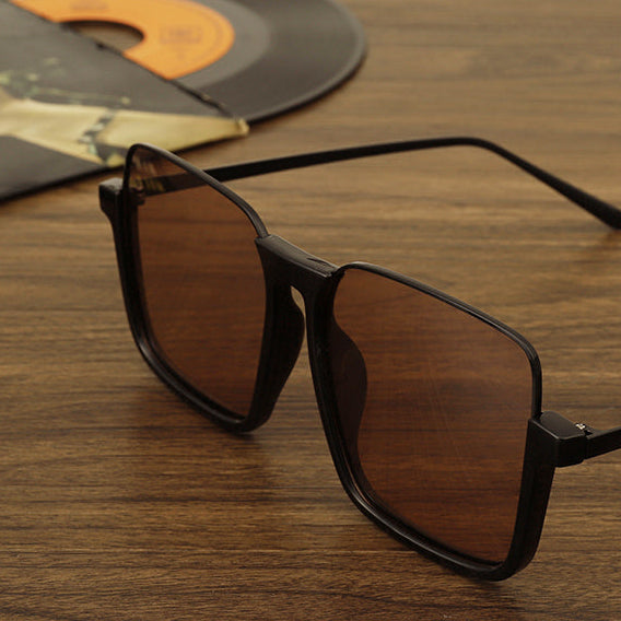 Sunglasses with brown lenses and black frames on a wooden surface