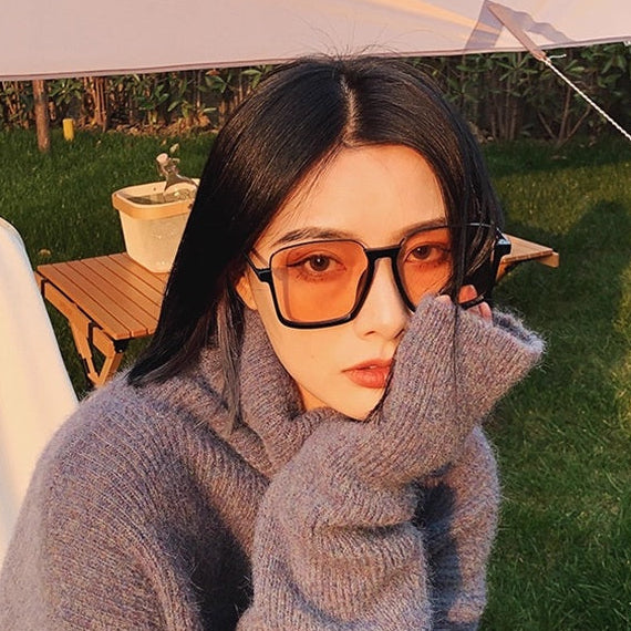 Person wearing a gray sweater and sunglasses outdoors
