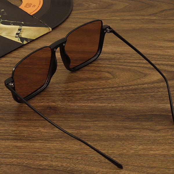 Sunglasses with brown lenses and black frames on a wooden surface