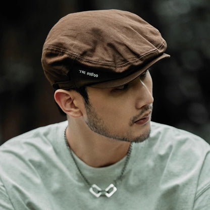 Man wearing a brown cap and light green shirt with a blurred background