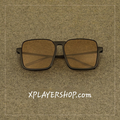 Sunglasses with brown lenses and black frames on a textured brown background with 'XPLAYERSHOP.com' text.