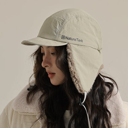Person wearing a beige cap with a hood and Nature Tek logo, standing against a neutral background.