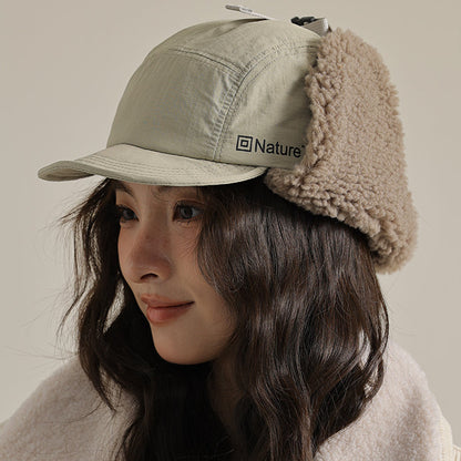 Person wearing a beige winter cap with fur trim and a matching jacket, with 'Nature' logo.